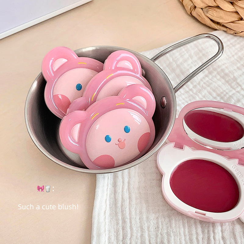 Pink bear-shaped blushes in a metal container on a beige surface.