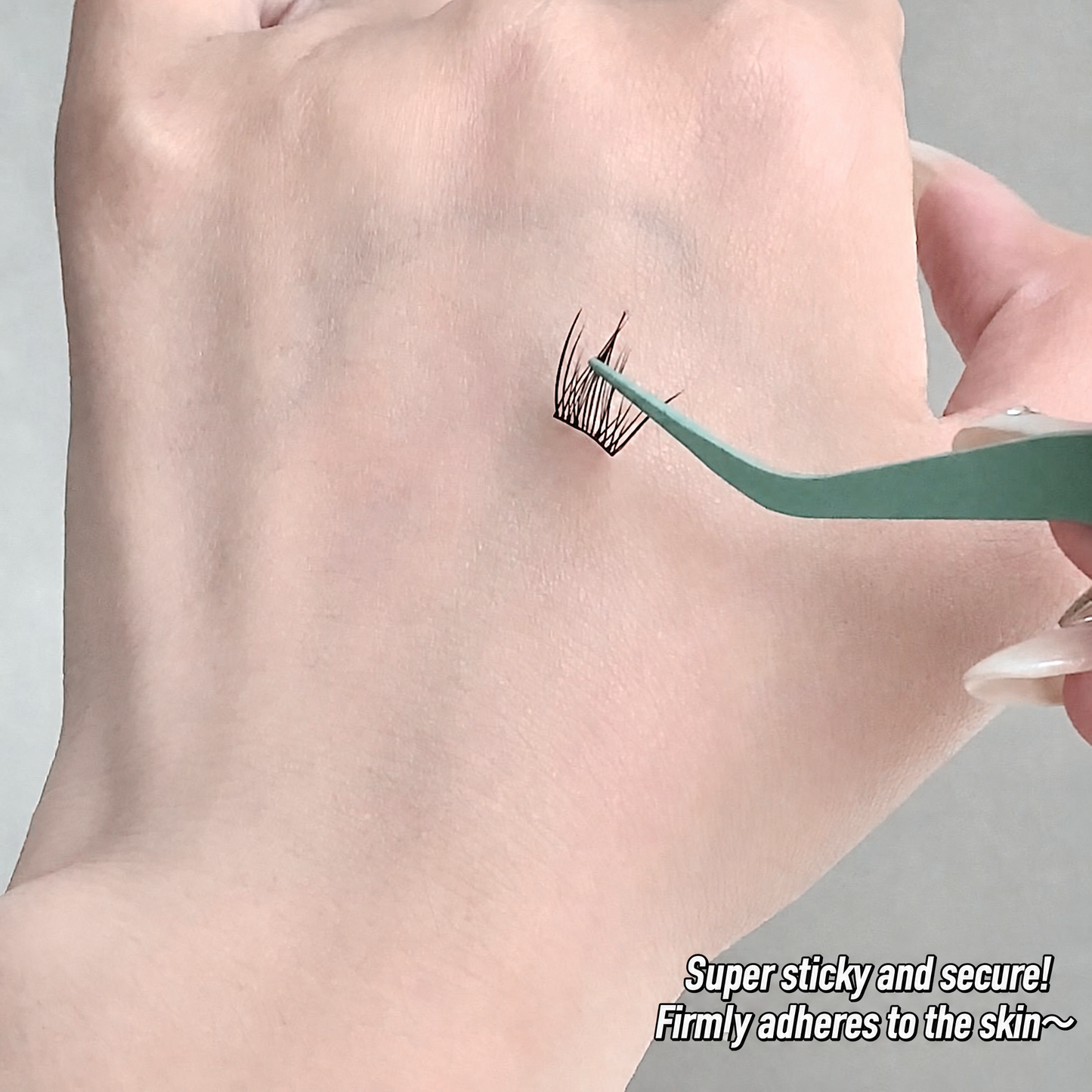 Eyelash extension being applied to a person's eyelid with text 'Super sticky and secure! Firmly adheres to the skin~'.