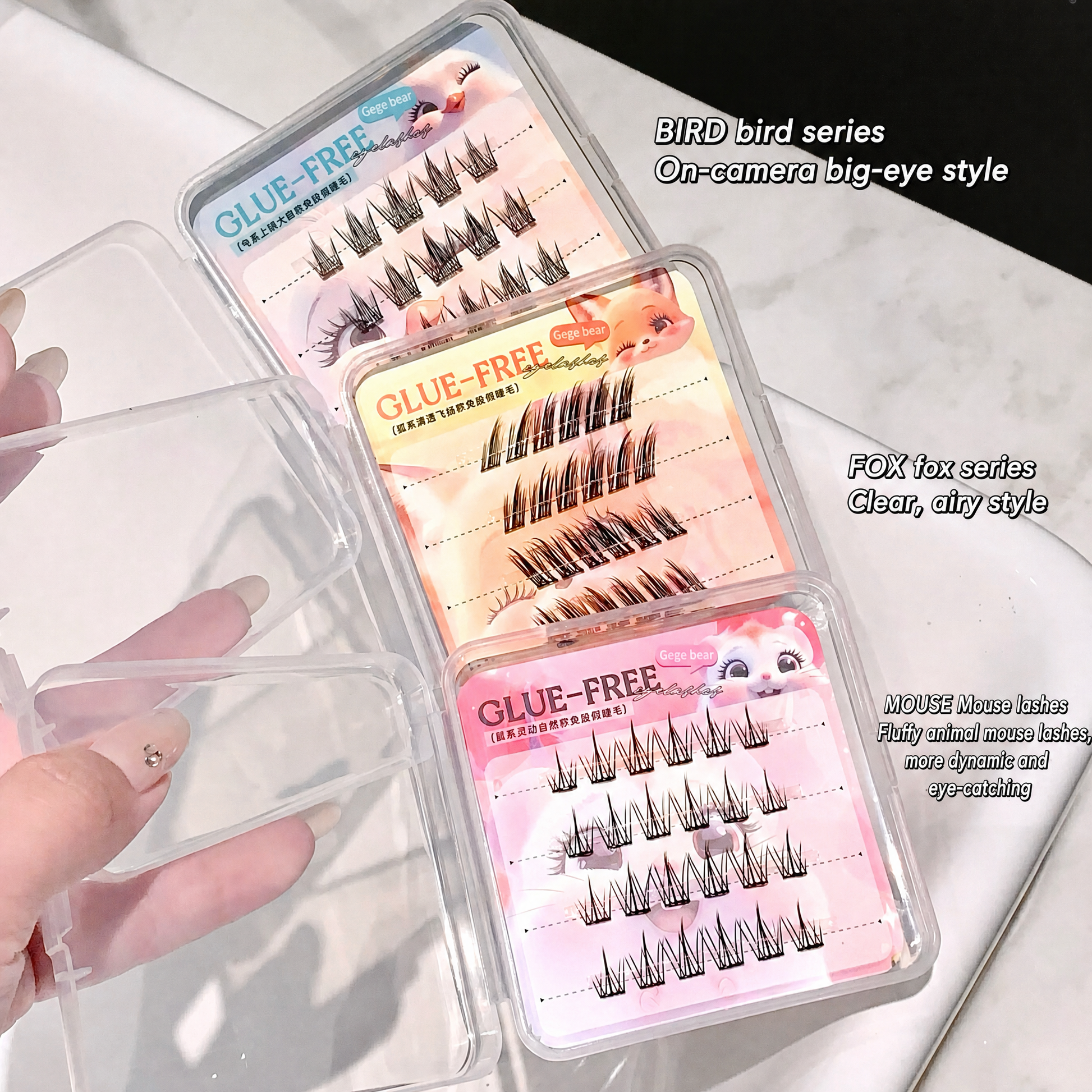 Set of false eyelashes in clear packaging with pink labels on a white surface.