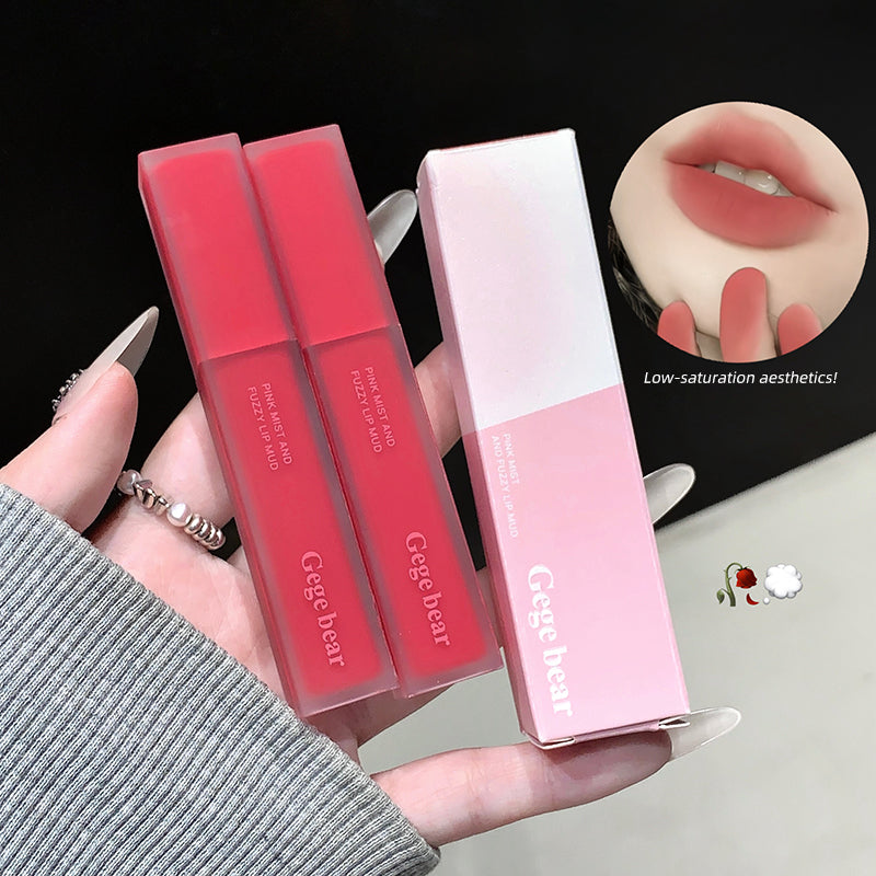 Two pink lip glosses with their packaging held by a hand, on a black background.