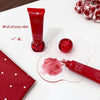 Red lip gloss tube with cherry design on a white surface