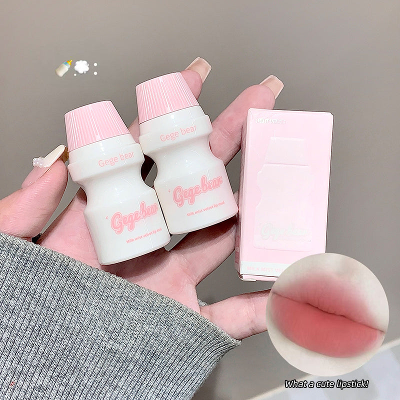 Two small white bottles with pink caps held by a hand, next to a pink box, on a neutral background.