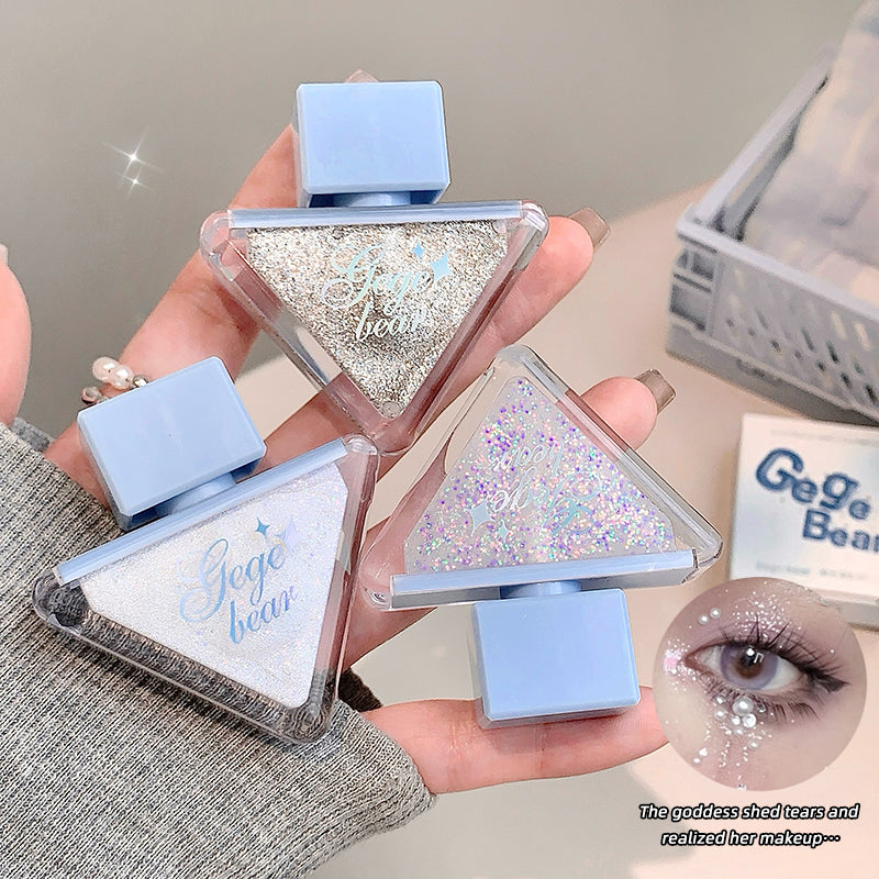 Three triangular makeup products with glittery texture held by a hand, branded 'Gege bear'.