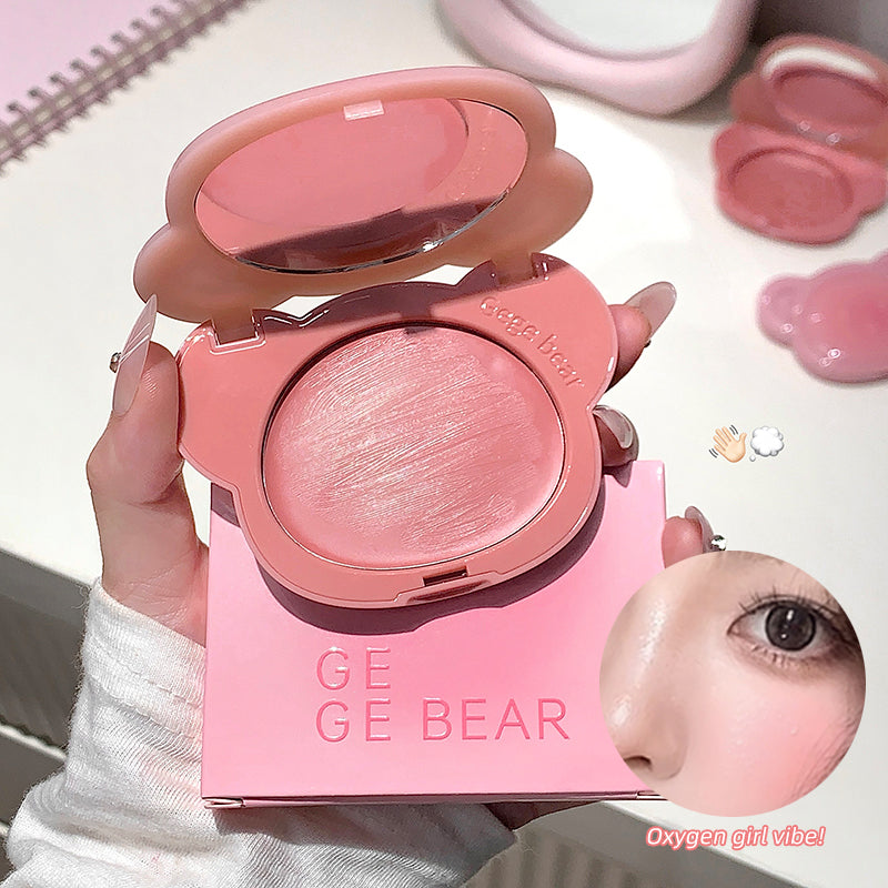 Pink makeup compact with 'GE GE BEAR' branding held by a hand, with blurred face in the corner.