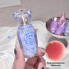 Small blue bottle with a textured design held by a hand, with a pink lip balm in the foreground.