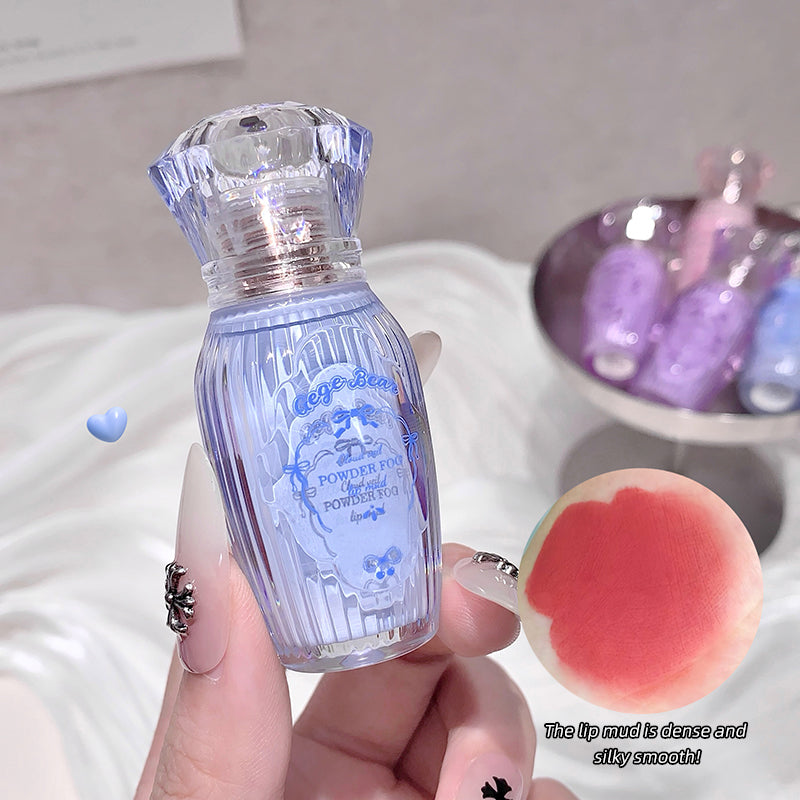 Small blue bottle with a textured design held by a hand, with a pink lip balm in the foreground.