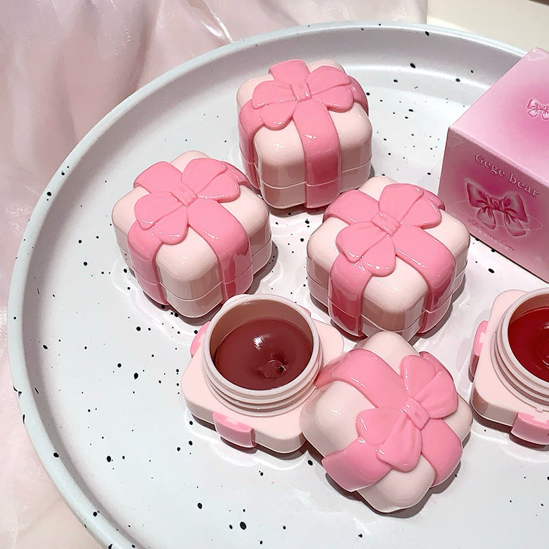 Pink floral containers with a small open container on a white speckled plate.
