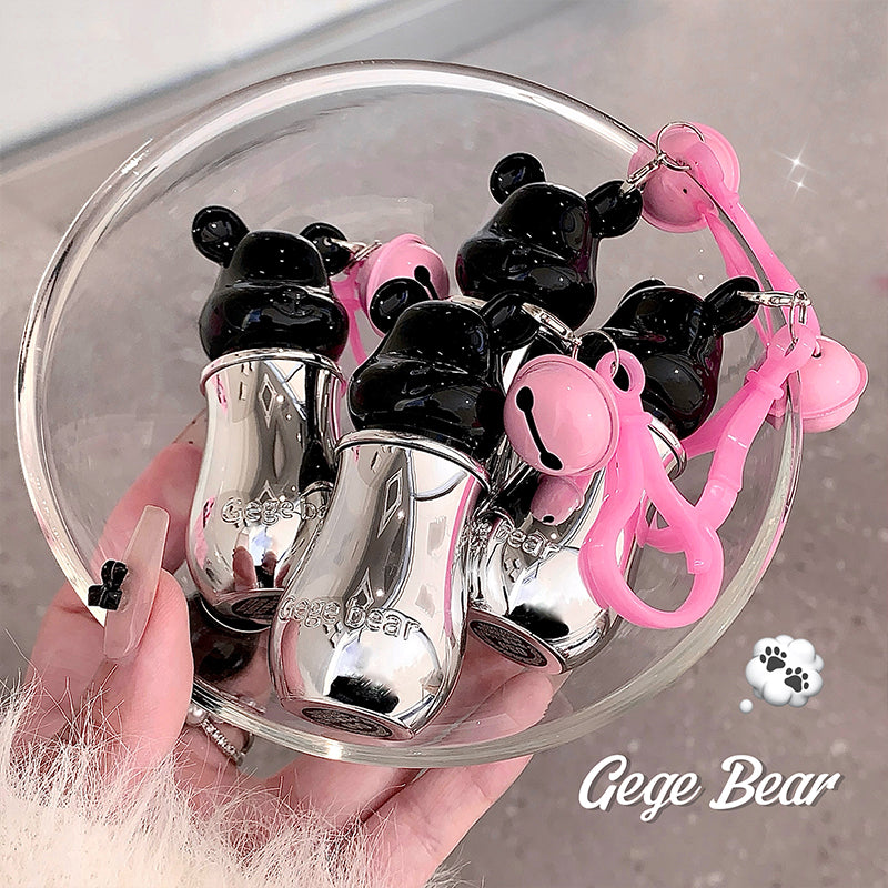 Black and silver bear-shaped nail polish bottles with pink accents in a clear dish, held by a hand.