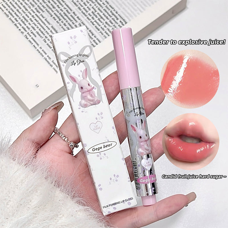 Lip gloss with bunny design held by a hand, close-up of product, and color swatch on a white background.