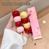 Candy-shaped lip mud on sticks with a pink box labeled 'Gee bear' on a wooden surface.