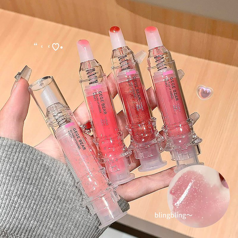 Hand holding multiple pink lip glosses with visible brand name on a wooden surface