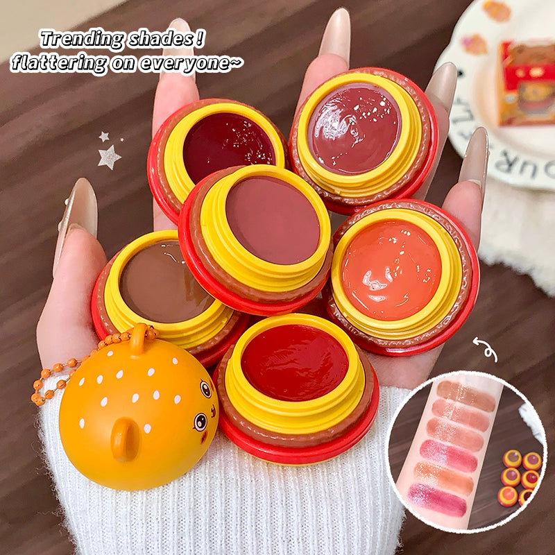 Colorful lip balm containers held by a hand with a brown background