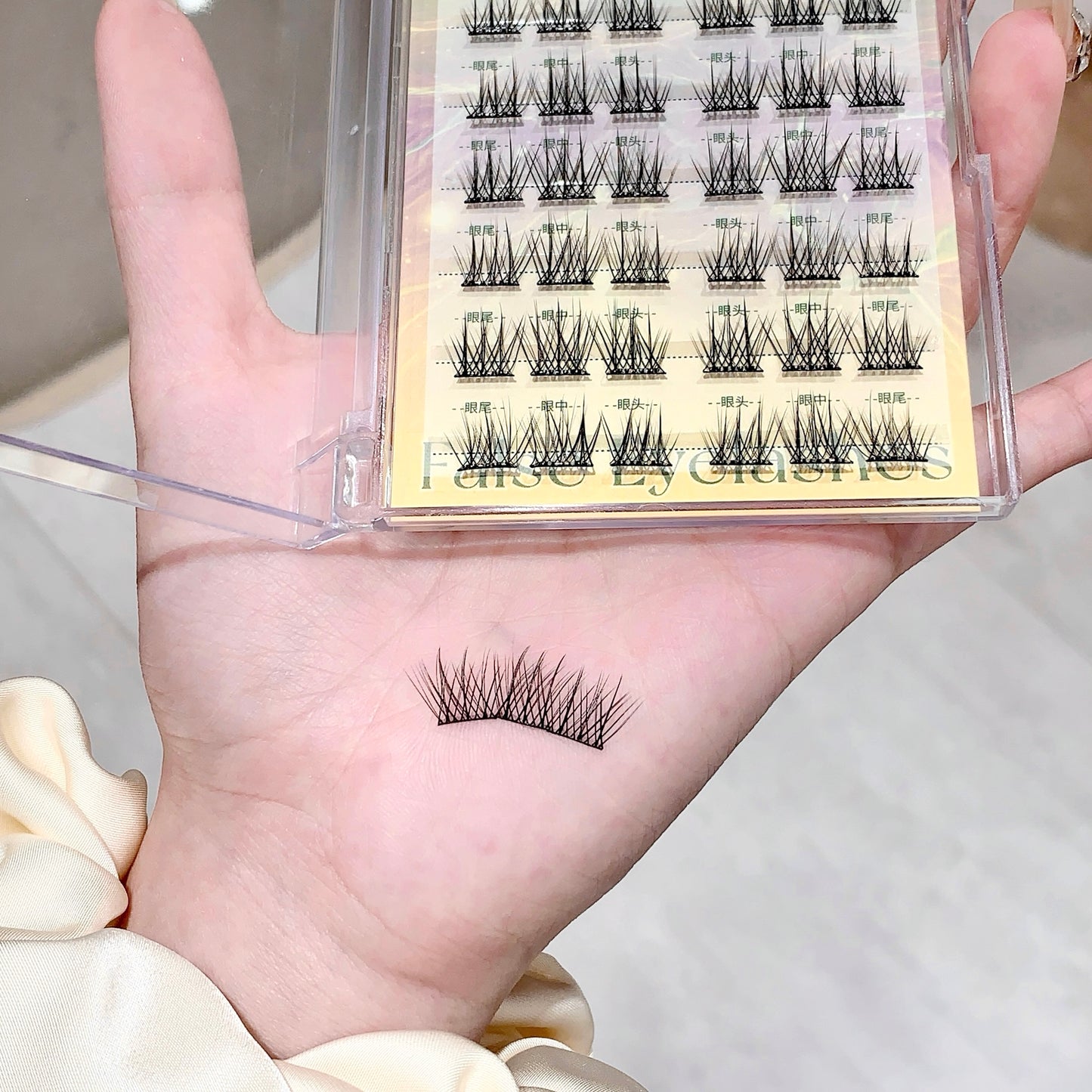 Set of false eyelashes with a clear case held in a hand.