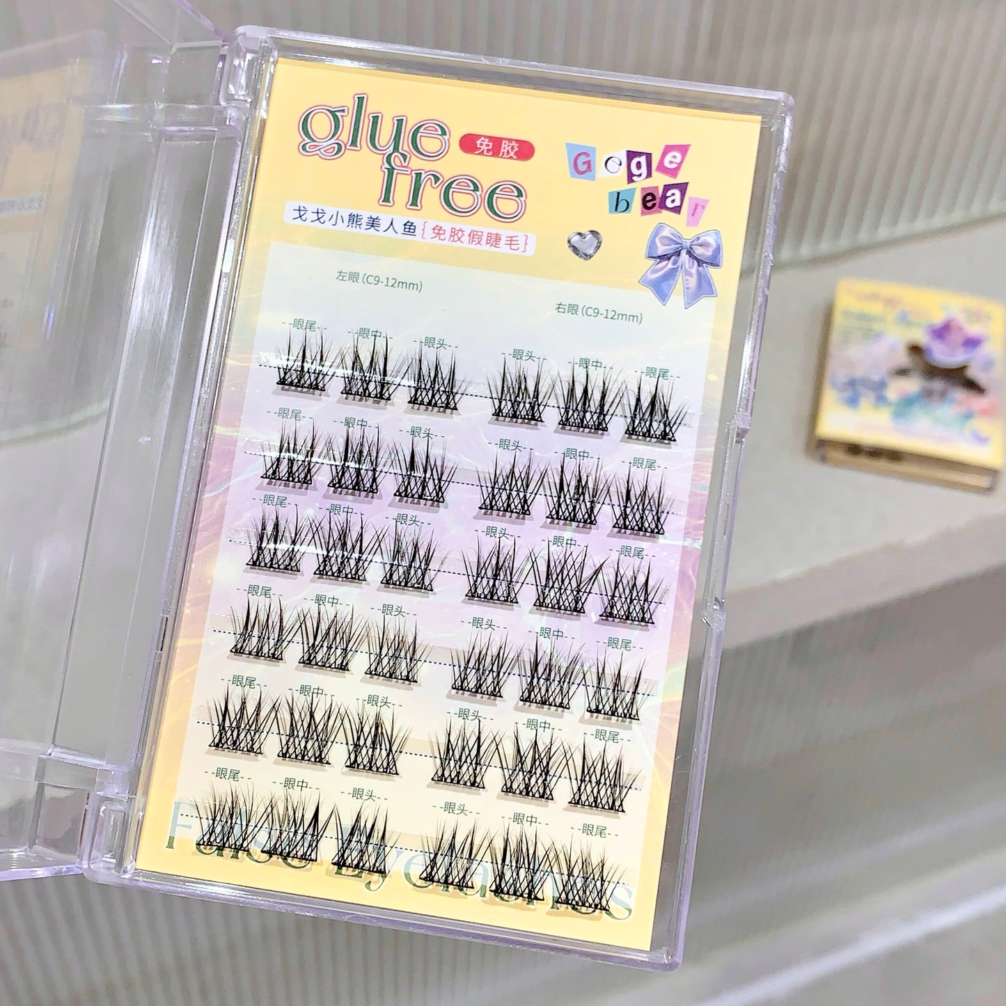 Eyelash extension set with 'glue free' label on a clear stand.