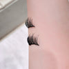 False eyelashes applied to a person's upper eyelid on a neutral background