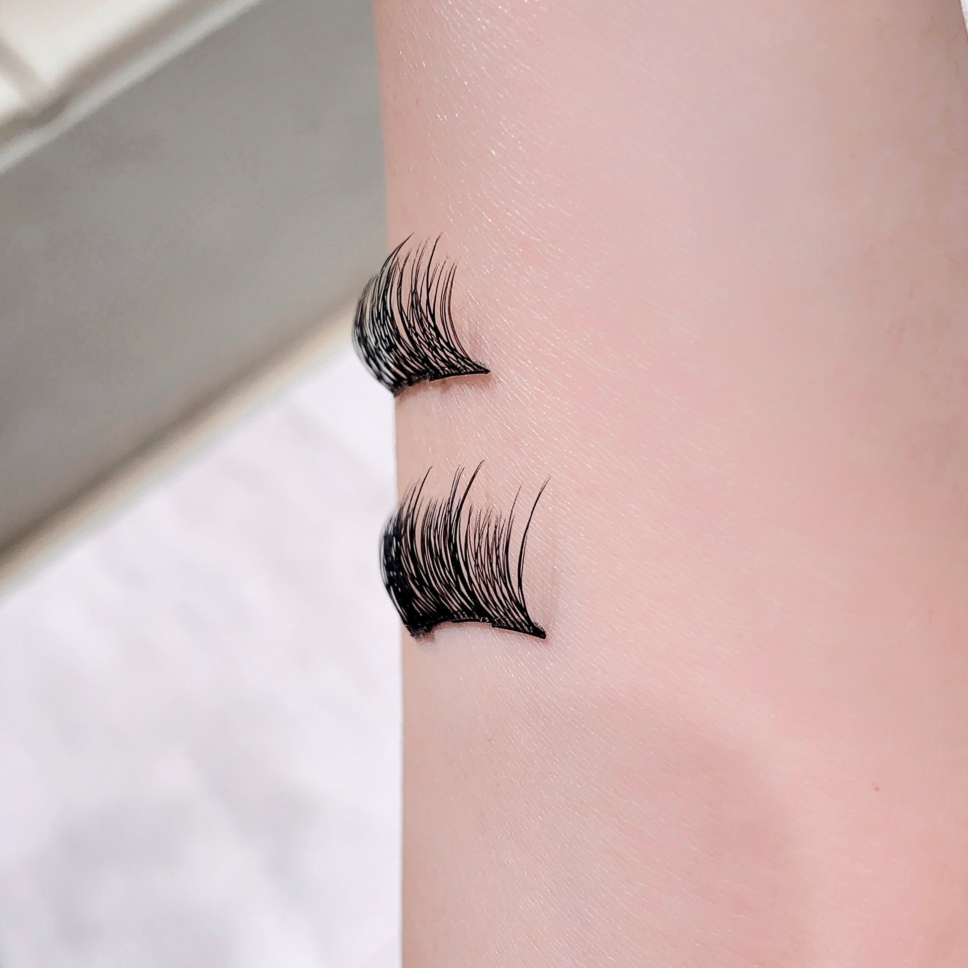False eyelashes applied to a person's upper eyelid on a neutral background