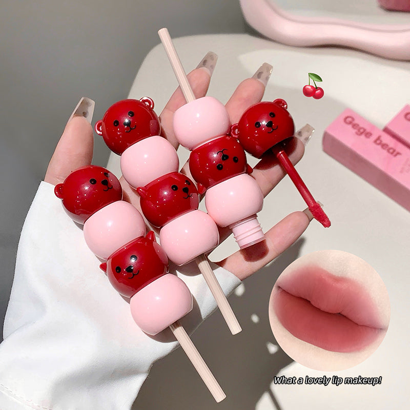 Makeup product shaped like a skewer with red and pink items, resembling lollipops and cherries.