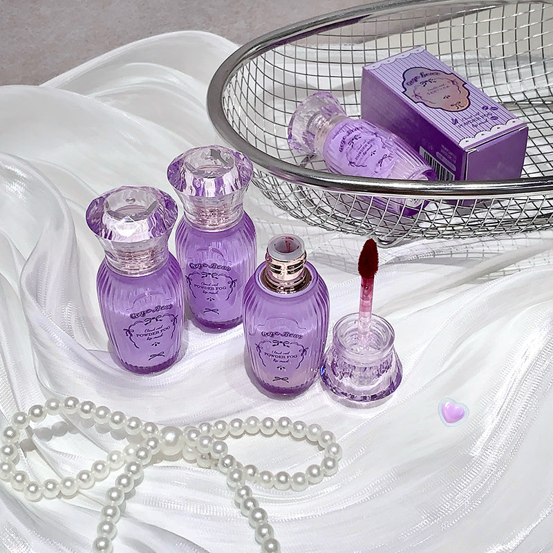 Purple cosmetic products on a white fabric background