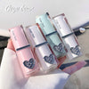 Four lip glosses with heart-shaped designs on a white surface, branded 'Gege bear'.