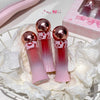 Three pink and red gradient lip glosses with rose gold caps on a white floral background.