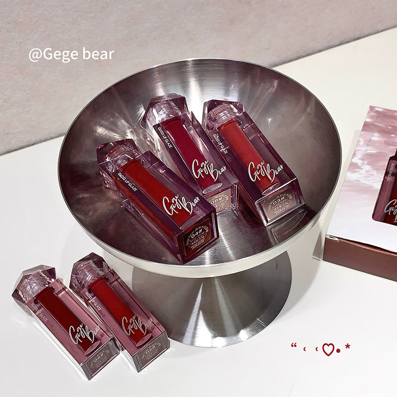 Lip glosses on a metallic stand with 'Gege Bear' branding.