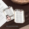 False eyelashes in a clear plastic case on a wooden surface with an open book.