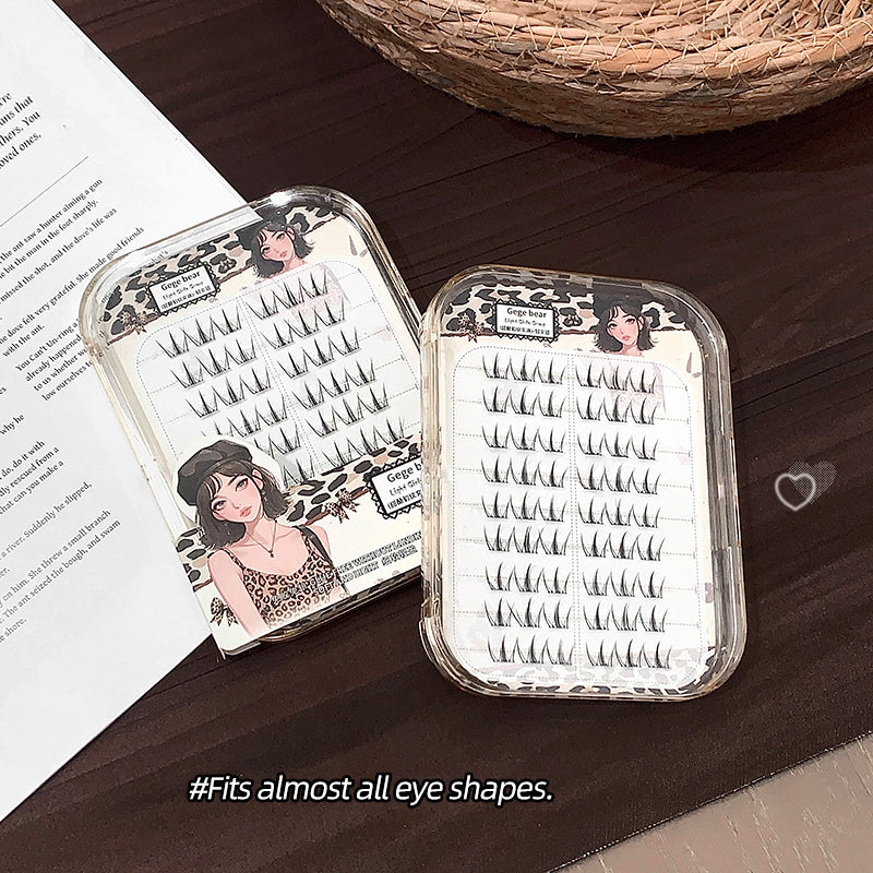 False eyelashes in a clear plastic case on a wooden surface with an open book.