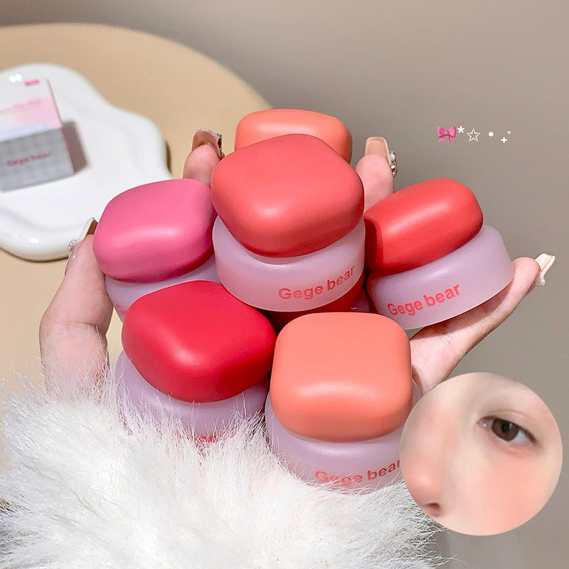 Hand holding small jars of pink and red lip balm with 'Gega bear' branding.