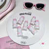 White containers with pink lids on a 'merciii' plate, accompanied by pink sunglasses.