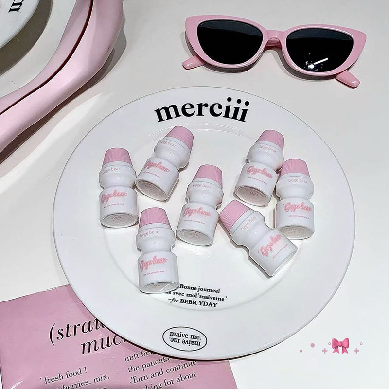White containers with pink lids on a 'merciii' plate, accompanied by pink sunglasses.