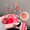 Set of lip glosses with applicators held by a hand, close-up view.