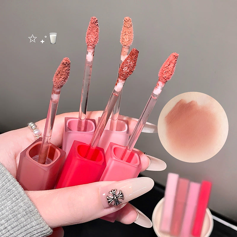 Set of lip glosses with applicators held by a hand, close-up view.