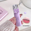 Purple lipstick with a bow design held by a hand, with a close-up of the lipstick color on a pink background.