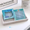 False eyelashes in a box on a table with a coffee mug and newspaper in the background
