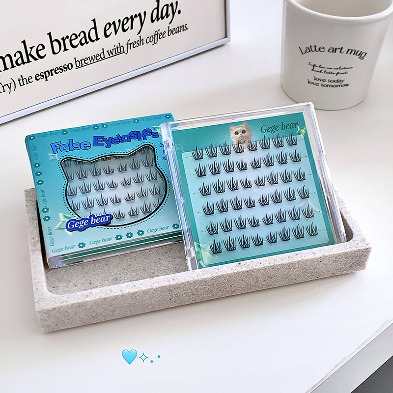 False eyelashes in a box on a table with a coffee mug and newspaper in the background