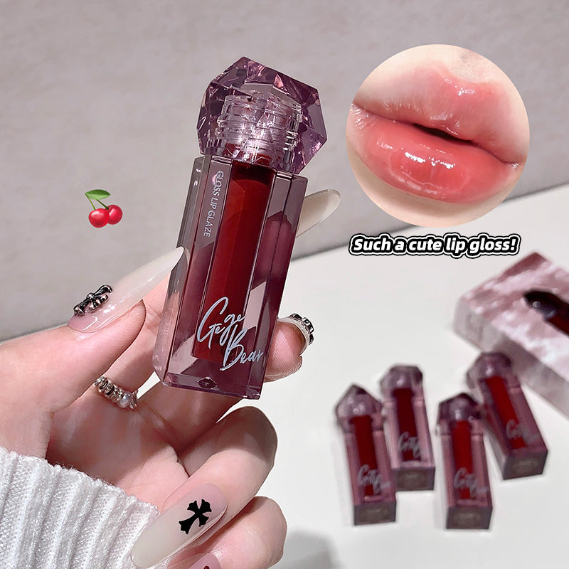 Lip gloss with a decorative cap held by a hand, close-up of lips with gloss, and additional lip glosses in the background.