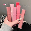 Hand holding multiple pink lip glosses with visible brand name on a neutral background