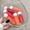 Colorful lip balms in a metal basket with a hand holding one.