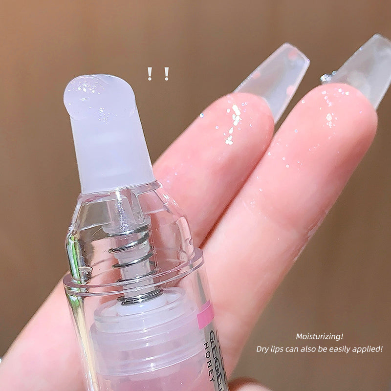 Lip balm with a clear container held between fingers against a brown background