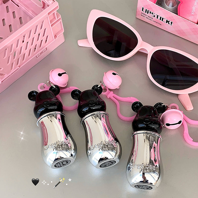 Silver lip balm with panda design, pink sunglasses, and pink basket on gray surface