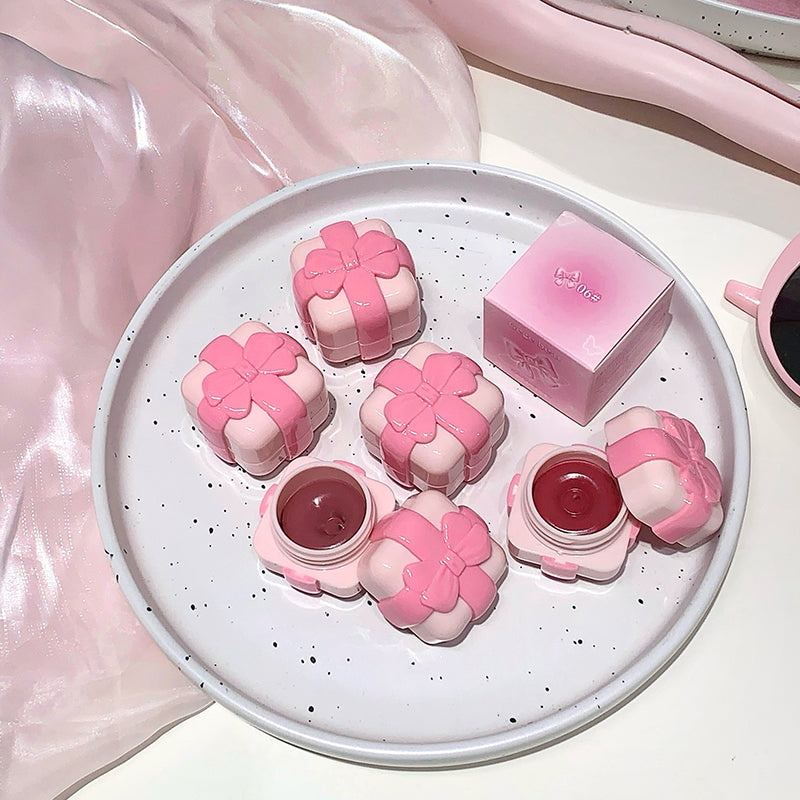 Pink floral lip balm containers on a white plate with a pink box in the background.