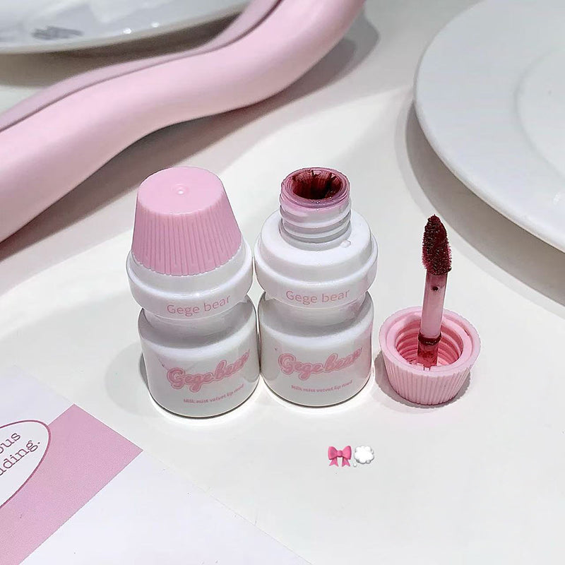 Set of white cosmetic bottles with pink caps on a light surface