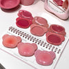 Pink makeup products on a white surface with a notebook