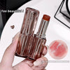 Lipstick with clear casing held by a hand, close-up on a white background.