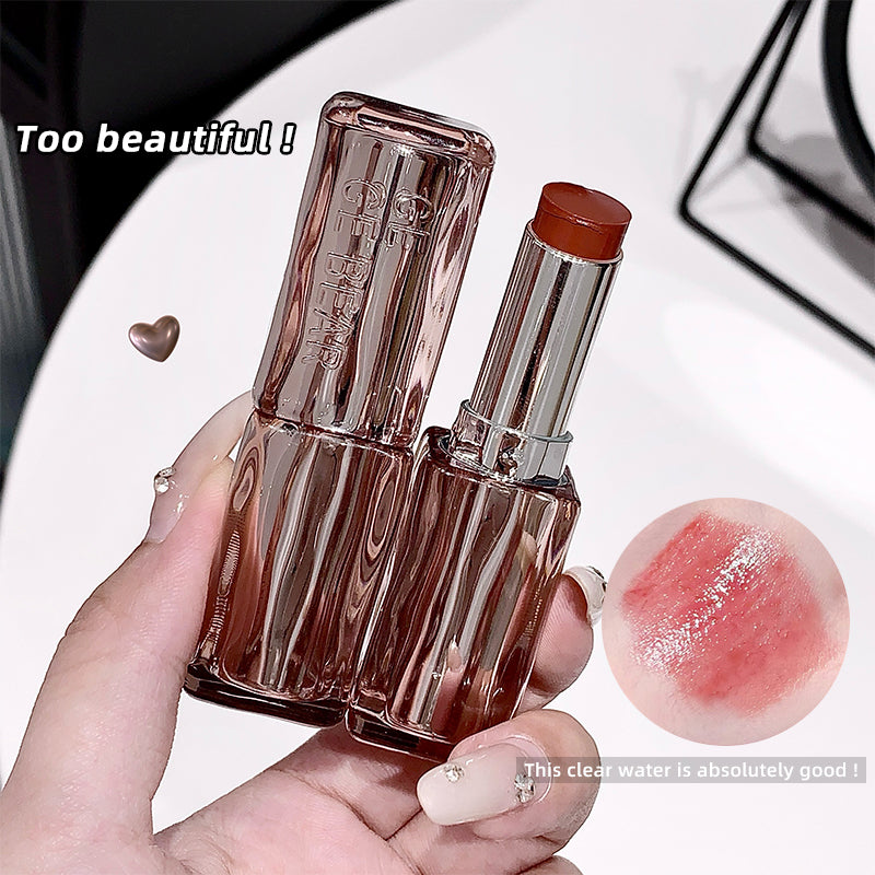 Lipstick with clear casing held by a hand, close-up on a white background.