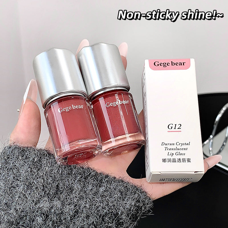 Two Gege bear lip gloss bottles and their packaging held by a hand.