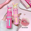 Two cartoon-themed lip glosses held by a hand on a pink background with a close-up of lips.