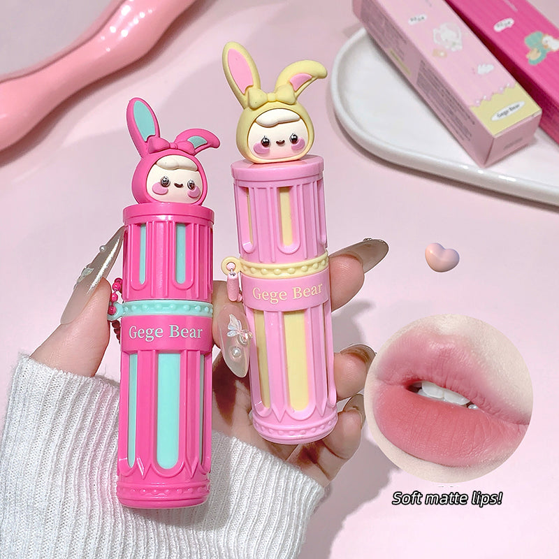 Two cartoon-themed lip glosses held by a hand on a pink background with a close-up of lips.
