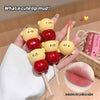Lip mud on a stick with bear and cherry design held by a hand, with text 'What a cute lip mud!' and 'Suitable for yellow skin!'.