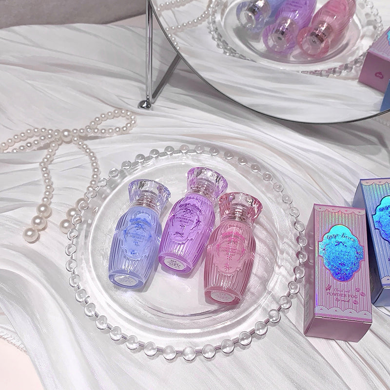 Three small bottles of perfume on a decorative tray with a mirror and packaging in the background.